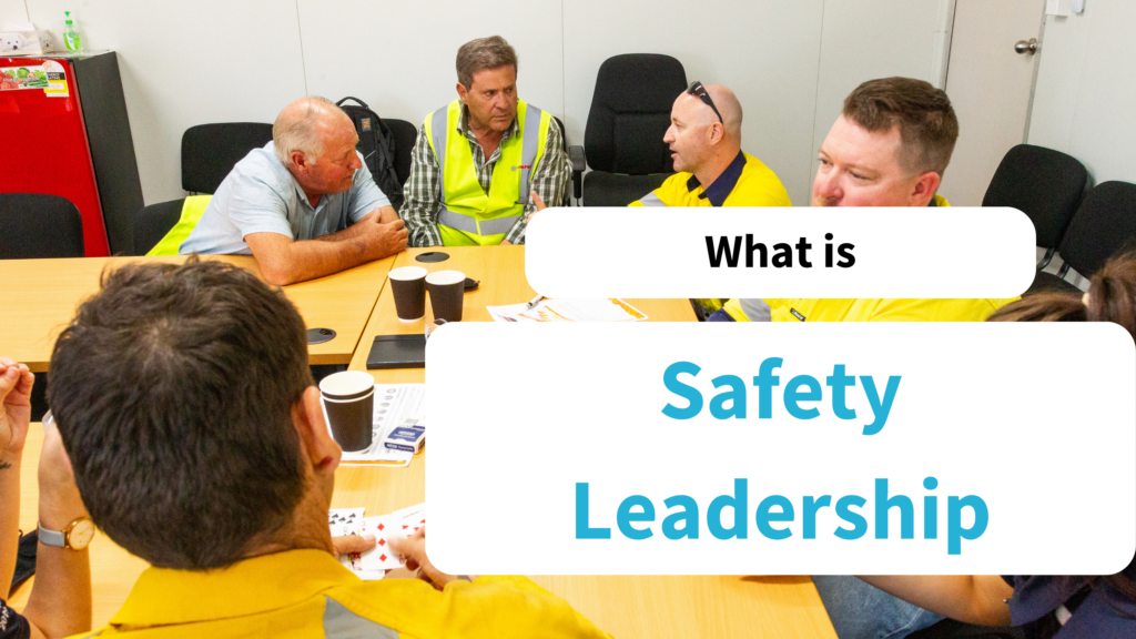 Text says: What is Safety Leadership. The text overlays an image of a group of workers speaking.